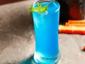 Niebieski drink z blue curacao, lodem i miętą, gotowy do podania.