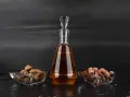 Amaretto co to? Bursztynowy likier w karafce, obok miseczki z migdałami i orzechami laskowymi.