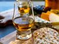 Szklanka whisky i sery na desce. Idealne na degustacje whisky online.
