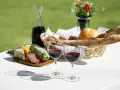 Dwa kieliszki pełne rubinowego pinot noir wina, obok deska serów, wędlin i kosz świeżego pieczywa.