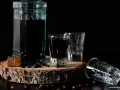Kahlúa co to? Ciemny likier kawowy w butelce i kieliszkach, ziarna kawy i kawałek czekolady na drewnianym plastrze.