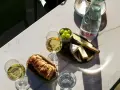 Dwa kieliszki orzeźwiającego gruner veltliner wino, chrupiąca bagietka, ser i winogrona na marmurowym stole.