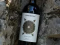 Butelka wina Altadonna Assalto Toscana, być może najdroższe wino w Polsce, spoczywa wśród kamieni.