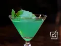 Zielony koktajl z miętą w kieliszku, idealny na orzeźwienie. Z czym pić? Z pewnością z lodem i odrobiną limonki!