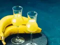 Dwa kieliszki z żółtym likierem bananowym, obok pęk bananów. Idealny na domowy likier bananowy przepis.