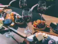 Degustacja merlot: jakie to wino? Kieliszki pełne czerwonego wina, deska serów, winogrona, oliwki i pieczywo tworzą idealną kompozycję.