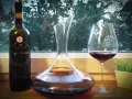 Butelka wina Egri Bikavér, karafka i kieliszek z czerwonym winem. Czas na degustację wina bycza krew.