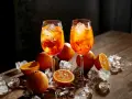 Dwa kieliszki orzeźwiającego aperol z colą, ozdobione pomarańczami i lodem, kuszą letnim smakiem.