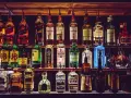Różnorodne podstawowe alkohole do drinków: whisky, gin, tequila, likiery, stoją na półkach baru, gotowe do przygotowania koktajli.
