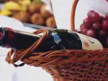 Koszyk piknikowy z butelką wina, winogronami i owocami w tle. Idealny zestaw, ale jaka woda do wina?