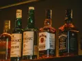 Rzędy butelek whisky: Laphroaig (43% vol.), Jim Beam (40% vol.) i Jack Daniel's (40% vol.).
