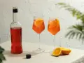 Dwa orzeźwiające drinki Aperol z plastrami pomarańczy i butelka Aperolu. Idealne na letnie popołudnie.