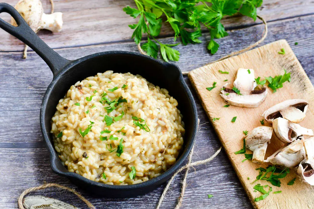 Kremowe risotto z grzybami, posypane natką pietruszki. Idealne, gdy szukasz czegoś co zamiast wina do risotto.