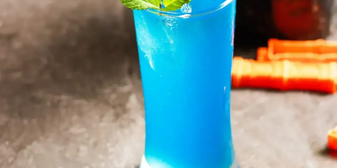 Niebieski drink z blue curacao, lodem i miętą, gotowy do podania.