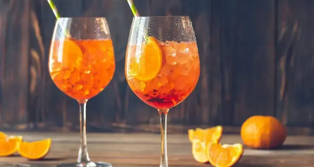Dwa kieliszki orzeźwiającego Aperol Spritz z pomarańczą i słomkami. Idealny aperol przepis na lato.