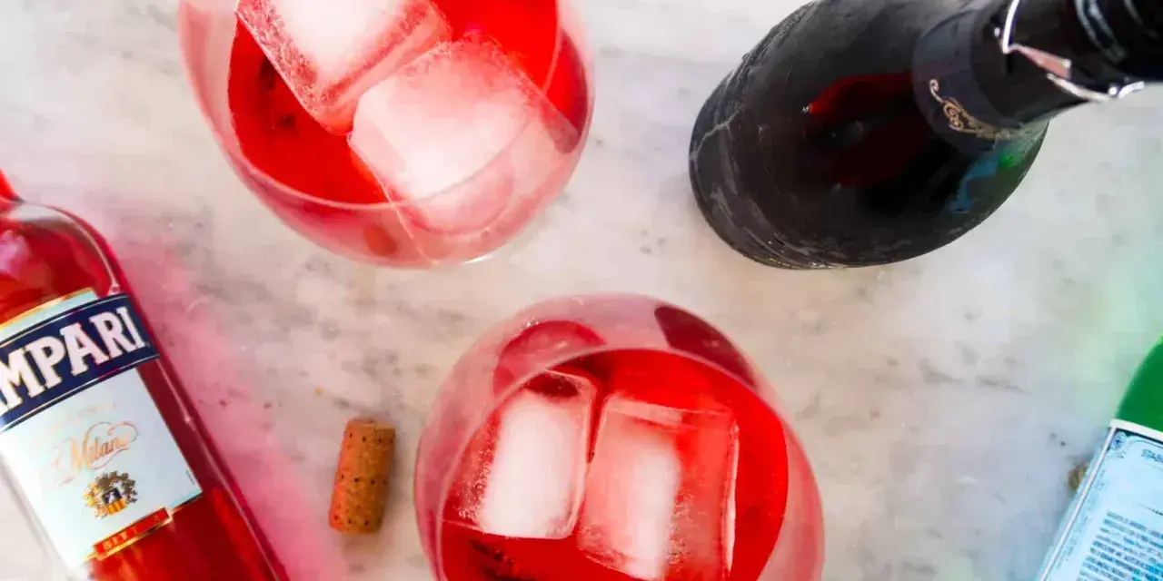 Dwa drinki z Campari, lodem i butelką prosecco. Idealne na letnie popołudnie. Campari z czym pić? Z bąbelkami!