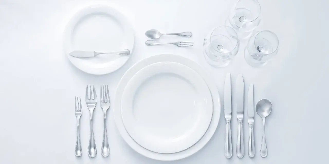Eleganckie nakrycie stołu: jak ustawić szklanki i kieliszki. Widoczne talerze, sztućce i kieliszki do wina.