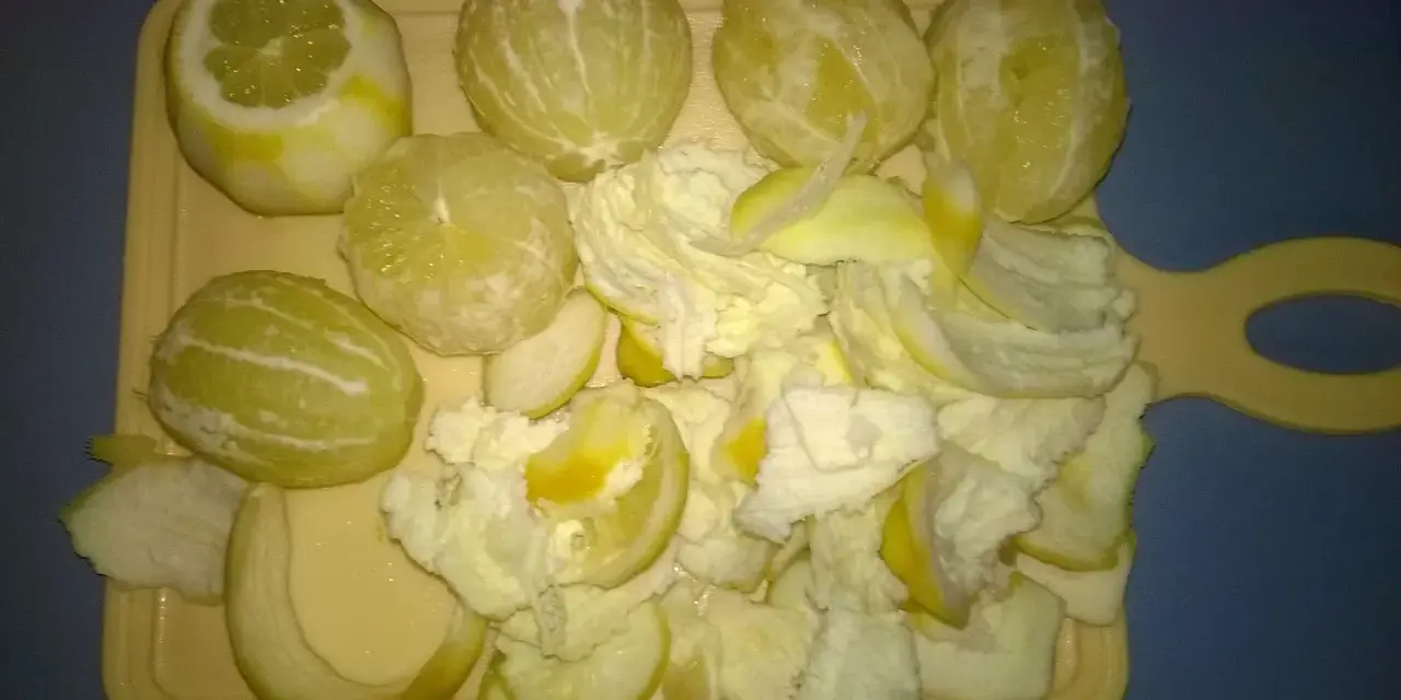 Przygotowanie do zrobienia cytrynówki: obrane cytryny i skórki na desce.