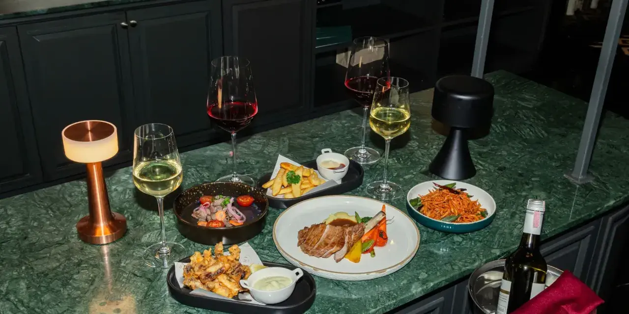 Elegancka kolacja z daniami i winem. Czy to chardonnay, jakie to wino? Obok kieliszki z białym i czerwonym winem, mięso, frytki i sałatka.