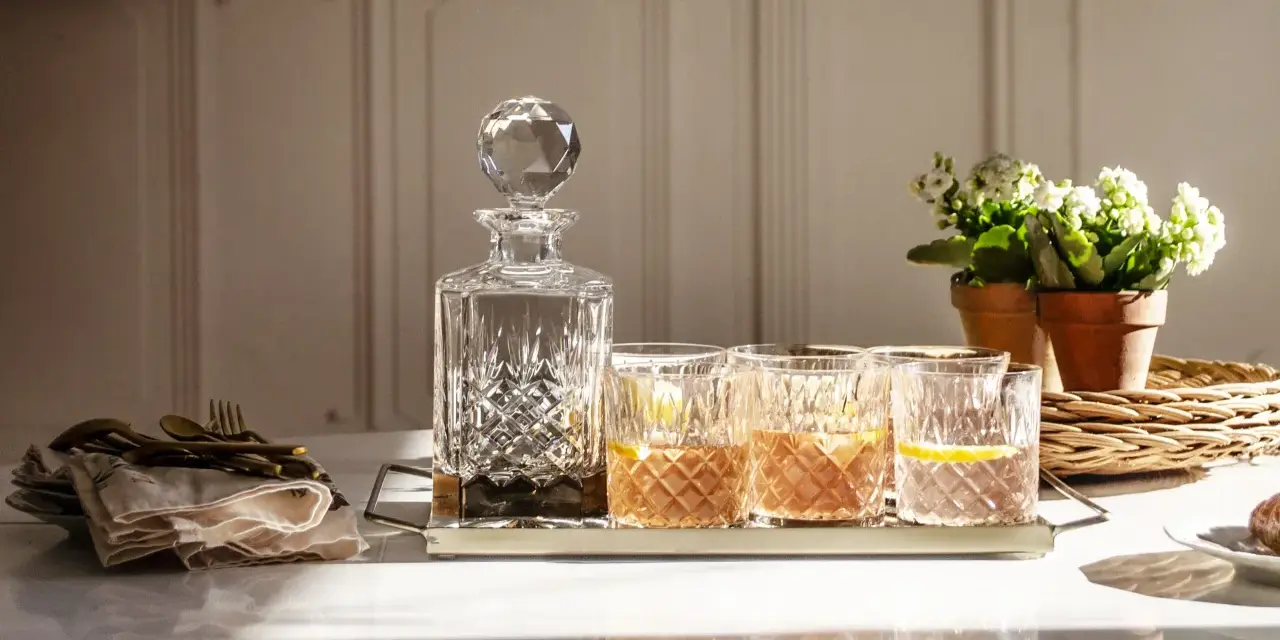 Elegancka karafka i szklanki z drinkami, idealne do serwowania bourbonu. Z czym pić bourbon? Z lodem i cytryną, jak na zdjęciu.