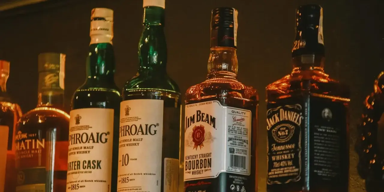 Rzędy butelek whisky: Laphroaig (43% vol.), Jim Beam (40% vol.) i Jack Daniel's (40% vol.).