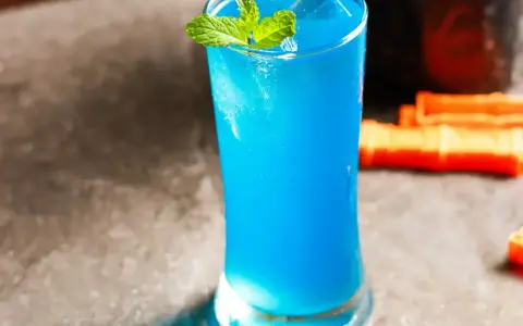 Niebieski drink z blue curacao, lodem i miętą, gotowy do podania.