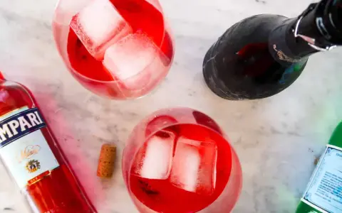 Dwa drinki z Campari, lodem i butelką prosecco. Idealne na letnie popołudnie. Campari z czym pić? Z bąbelkami!