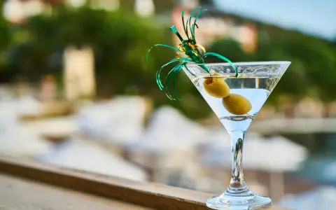 Idealny drink na wakacje: schłodzone martini z dwiema oliwkami, ozdobione zieloną wstążką. Idealne co do martini.