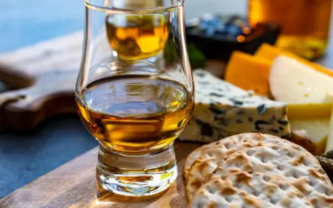 Szklanka whisky i sery na desce. Idealne na degustacje whisky online.