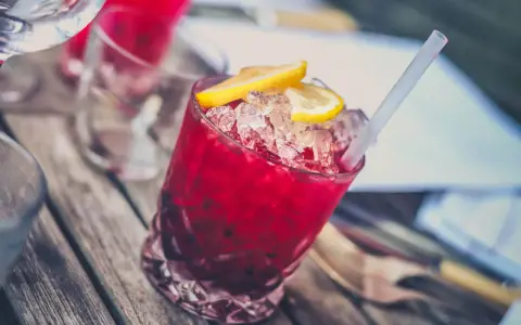 Czerwony drink z lodem i cytryną, z pewnością z dodatkiem grenadyny. Co to jest grenadyna? To syrop z granatów, idealny do koktajli.