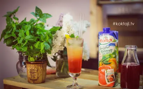 Kolorowy drink z lodem i słomkami, obok sok grejpfrutowy Hortex i butelka z ciemnym płynem.