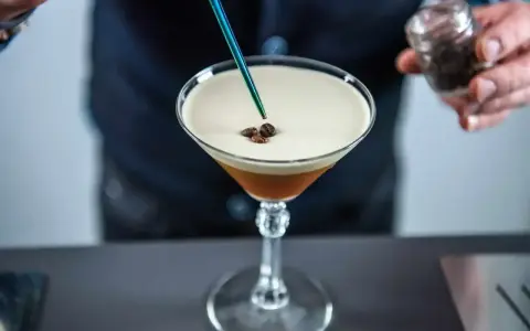 Barman dodaje ziarna kawy do drinka z pianką, idealny likier 43 zamiennik.