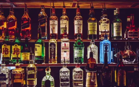 Półki pełne alkoholi, w tym butelki z napisem "The Macallan" i "The Glenlivet", sugerujące najlepsza polska whisky.