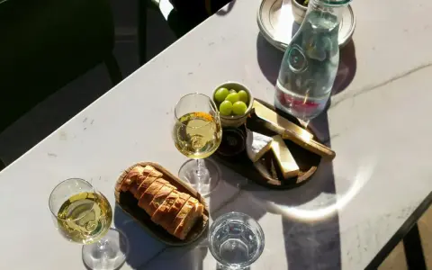 Dwa kieliszki orzeźwiającego gruner veltliner wino, chrupiąca bagietka, ser i winogrona na marmurowym stole.