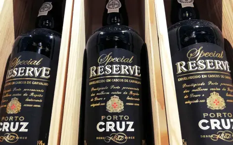 Trzy butelki półwytrawne wino portugalskie Porto Cruz Special Reserve w drewnianych skrzynkach.