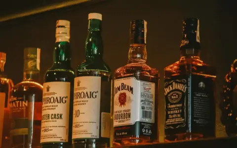 Rzędy butelek whisky: Laphroaig (43% vol.), Jim Beam (40% vol.) i Jack Daniel's (40% vol.).