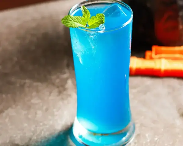 Niebieski drink z blue curacao, lodem i miętą, gotowy do podania.