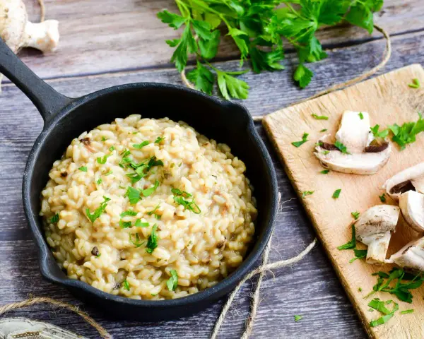 Kremowe risotto z grzybami, posypane natką pietruszki. Idealne, gdy szukasz czegoś co zamiast wina do risotto.