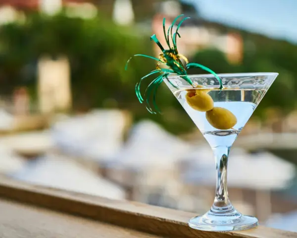 Idealny drink na wakacje: schłodzone martini z dwiema oliwkami, ozdobione zieloną wstążką. Idealne co do martini.