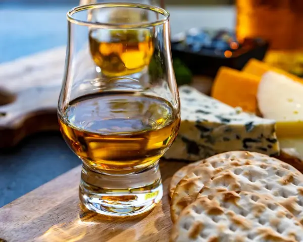 Szklanka whisky i sery na desce. Idealne na degustacje whisky online.