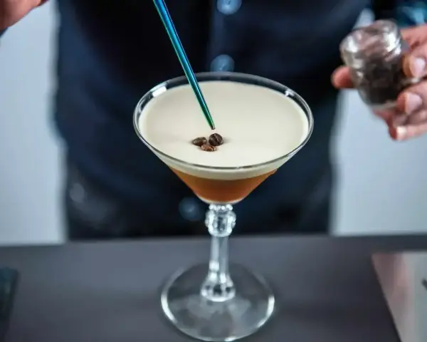 Barman dodaje ziarna kawy do drinka z pianką, idealny likier 43 zamiennik.