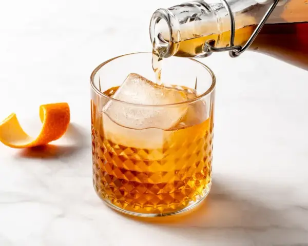 Likier amaretto z czym pić? Bursztynowy trunek z lodem i skórką pomarańczy, idealny do drinków.
