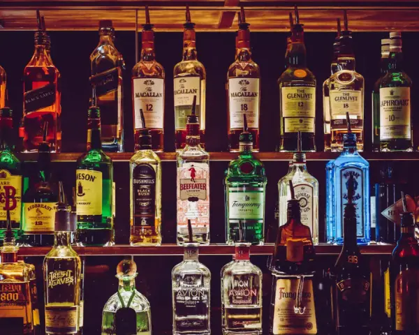Półki pełne alkoholi, w tym butelki z napisem "The Macallan" i "The Glenlivet", sugerujące najlepsza polska whisky.
