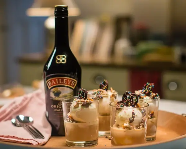 Butelka Baileys i cztery pucharki z lodami i czekoladowymi ozdobami. Idealny deser, by sprawdzić, baileys co to za smak!