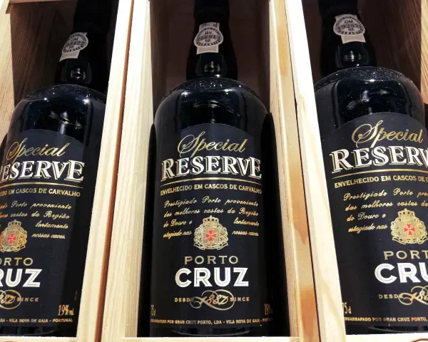 Trzy butelki półwytrawne wino portugalskie Porto Cruz Special Reserve w drewnianych skrzynkach.