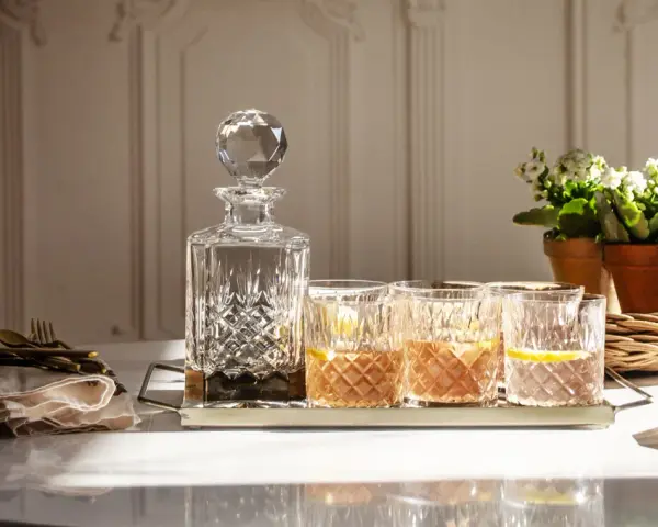 Elegancka karafka i szklanki z drinkami, idealne do serwowania bourbonu. Z czym pić bourbon? Z lodem i cytryną, jak na zdjęciu.