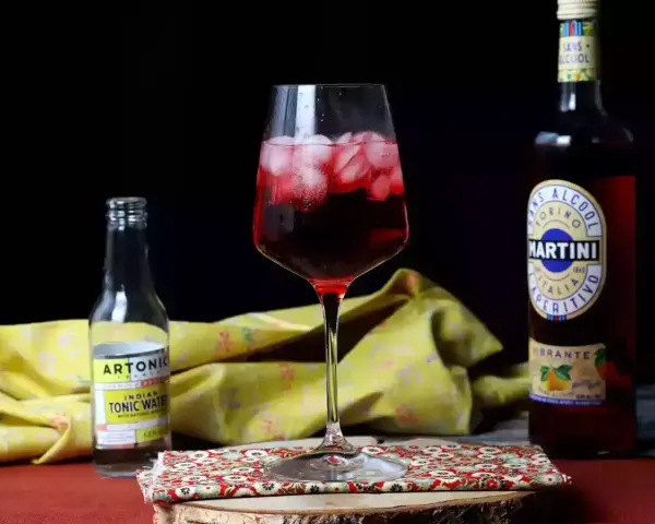 Orzeźwiający martini tonic drink z lodem, obok butelka toniku i Martini Vibrante.