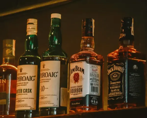 Rzędy butelek whisky: Laphroaig (43% vol.), Jim Beam (40% vol.) i Jack Daniel's (40% vol.).