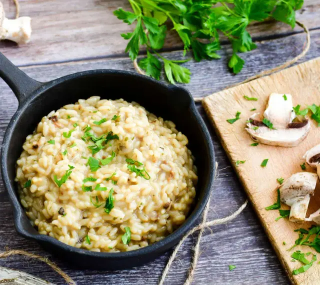 Kremowe risotto z grzybami, posypane natką pietruszki. Idealne, gdy szukasz czegoś co zamiast wina do risotto.