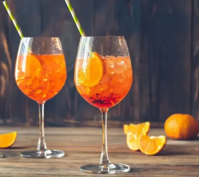 Dwa kieliszki orzeźwiającego Aperol Spritz z pomarańczą i słomkami. Idealny aperol przepis na lato.